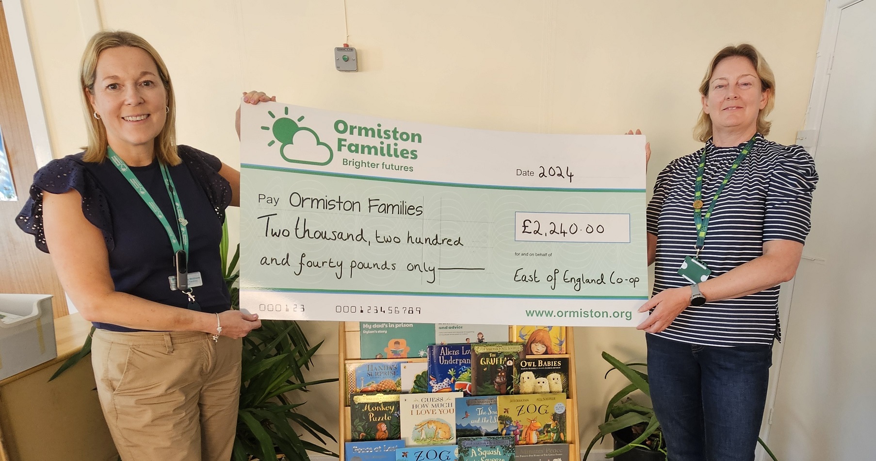 Two smiling women hold up a large cheque