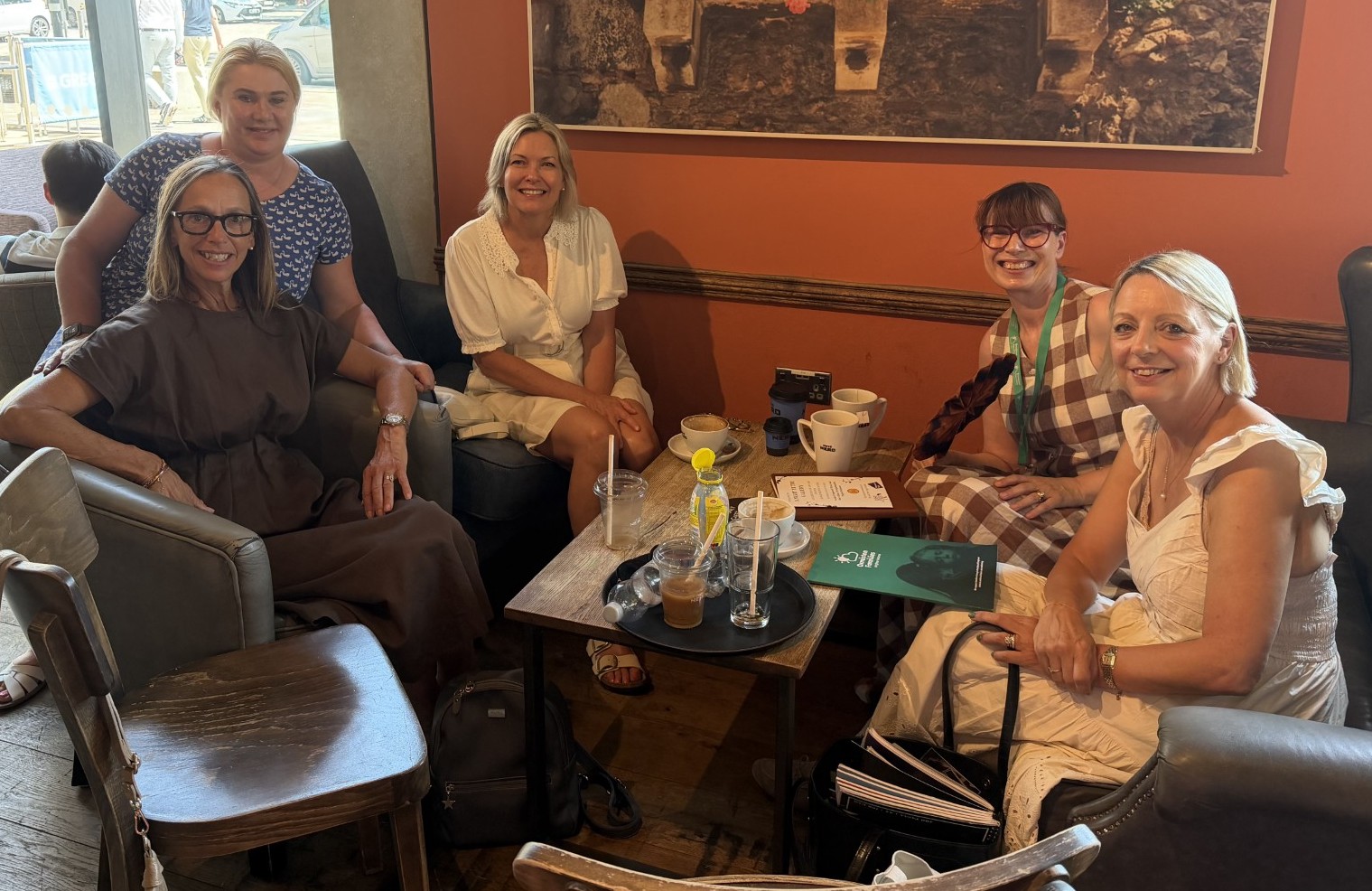 Five women sitting round a coffee table.